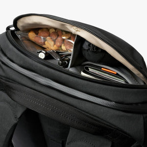 Open top pocket of a black Bellroy backpack showing organized snacks and personal items