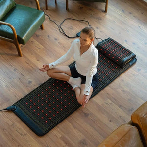 Woman sitting in lotus position on a HealthyLine infrared therapy mat with red light nodes