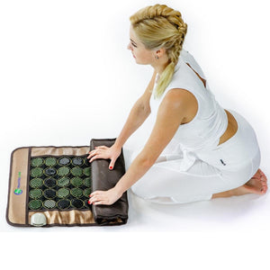 Woman kneeling and rolling up a Healthy Line infrared heating mat with circular stone discs