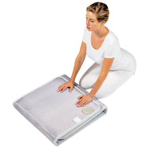 Woman kneeling and touching a folded HealthyLine infrared heating mat