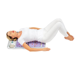 Person lying on a HealthyLine amethyst heating mat with knees bent