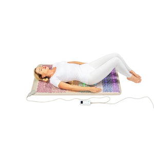 Person lying on a HealthyLine gemstone mat with LED lights and a digital controller