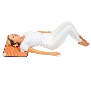 Woman lying on a HealthyLine infrared heating mat with her head resting on the device