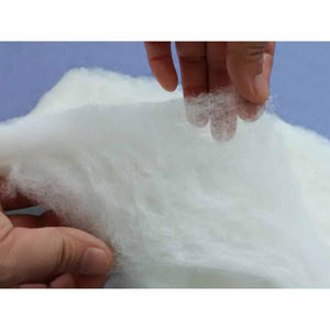 Hands holding white polyester fiberfill stuffing from HealthyLine