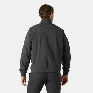 Back view of a person wearing a black Helly Hansen jacket with a high collar and ribbed cuffs