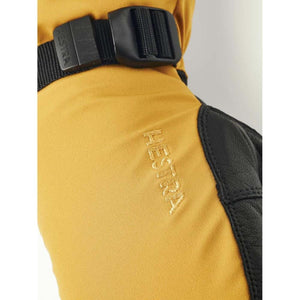 Close up of yellow Hestra glove with black leather palm and adjustable wrist strap