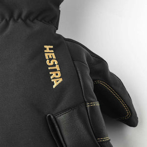 Black Hestra glove with gold embroidered logo and stitching