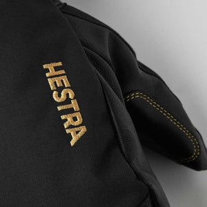 Black Hestra glove with gold embroidered logo and stitching