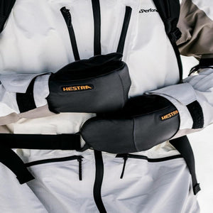 Person wearing Hestra black leather mittens with a white ski jacket