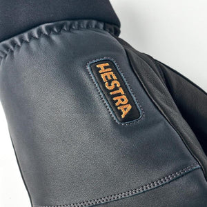 Close up of black leather Hestra glove with embroidered brand logo