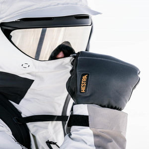 Person wearing Hestra black leather ski gloves with white jacket and ski goggles