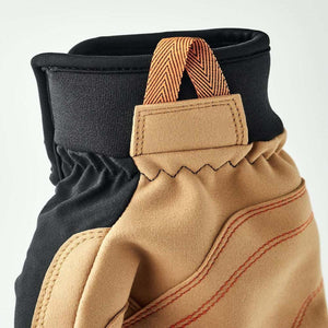 Close up of tan and black work glove cuff with orange pull tab