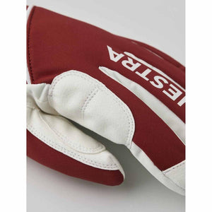 Close up of a red and white Hestra glove with white leather palm detail