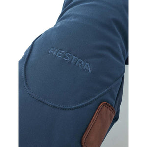 Close up of blue Hestra glove with embroidered logo and brown leather detail