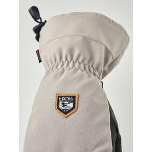 Beige Hestra mitten with a branded patch on the back of the hand