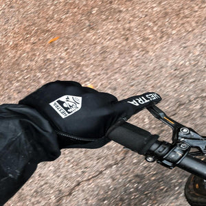 Person wearing black Hestra gloves while riding a bicycle on a paved path