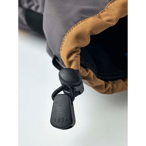 Close up of a grey and tan glove cuff with a black adjustable drawstring toggle featuring the number 1936