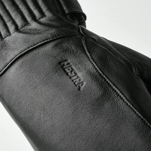 Close up of black Hestra leather glove with embossed logo