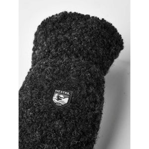 Close up of black Hestra wool mitten with brand logo patch