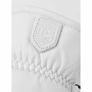 Close up of white Hestra leather glove with embossed brand logo patch