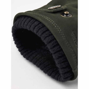 Close up of dark green suede glove cuff with black ribbed knit lining and metal snap button