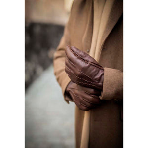 Person wearing brown leather gloves and a tan wool coat