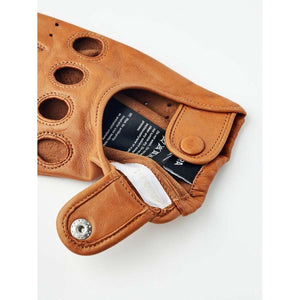 Hestra tan leather driving glove showing interior care label and snap button closure