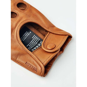 Close up of tan Hestra leather glove cuff with snap button and care label