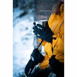 Person wearing Hestra gloves holding a metal mug outdoors in winter