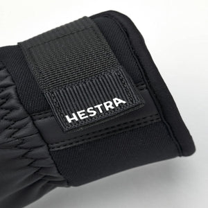 Black Hestra glove cuff with adjustable velcro strap and white logo