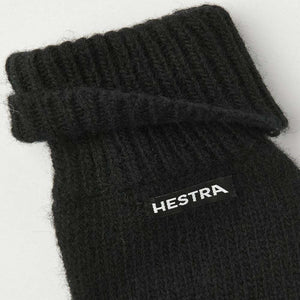 Black Hestra knit glove cuff with ribbed texture and brand label