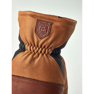 Tan leather Hestra glove cuff with elasticated wrist and embossed brand logo patch