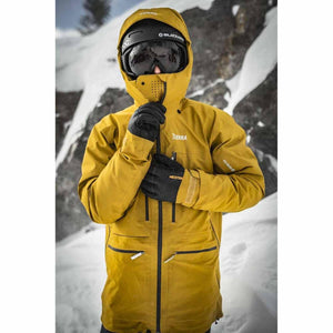 Person wearing a yellow jacket and Hestra black gloves in a snowy mountain environment
