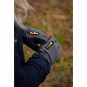 Person wearing grey Hestra gloves with black logo patch