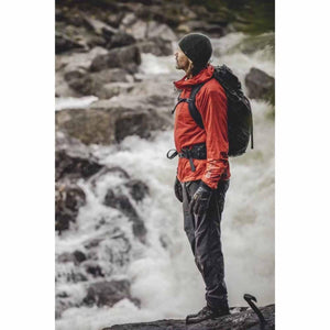 Hiker wearing Hestra gloves and red jacket standing by a waterfall