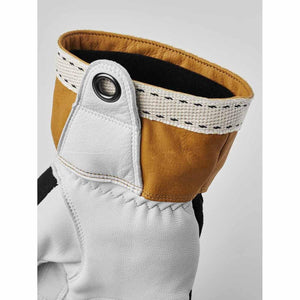 Close up of white and tan leather glove cuff with black metal eyelet