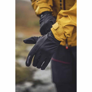 Person wearing black Hestra gloves with yellow jacket