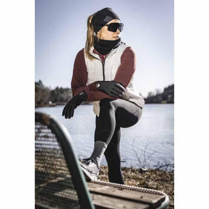 Person wearing Hestra black gloves and outdoor athletic gear resting foot on a park bench by a lake
