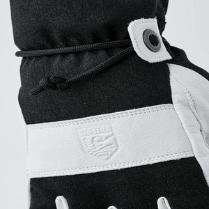 Black and white Hestra ski glove with adjustable drawstring cuff and embossed logo