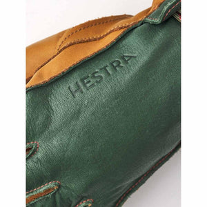 Close up of Hestra logo embossed on green and tan leather glove