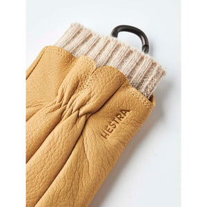 Tan leather Hestra glove with a ribbed knit cuff and black carabiner
