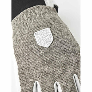 Close up of Hestra glove with textured grey fabric and brand logo patch