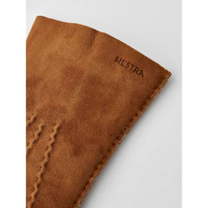 Tan suede Hestra glove cuff with embossed brand logo