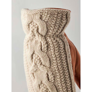 Close up of a beige cable knit wool glove with brown leather palm