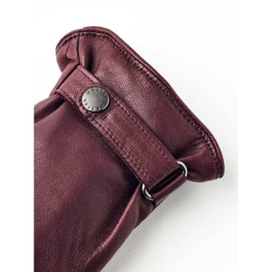 Close up of burgundy Hestra leather glove cuff with branded metal snap button