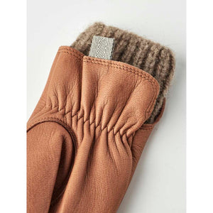 Hestra tan leather glove with a brown knitted wool cuff and a small woven brand label
