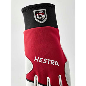 Red and white Hestra glove with black cuff and Hestra logo patch
