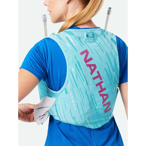 Person wearing a light blue Nathan hydration vest with two hydration tubes over shoulders