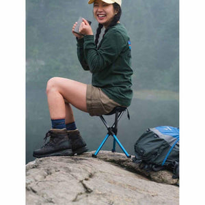 Hiker sitting on a Hillsound portable stool on a rocky cliffside