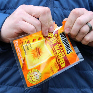 Hands opening a Hothands body and hand super warmer packet